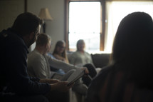 group of young adults sitting on a couch reading scripture 
