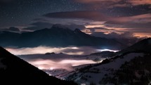 Magic of night sky and stars motion fast in winter alps mountains in foggy valley nature Astronomy Time-lapse
