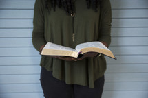 a woman looking down reading the pages of a Bible 