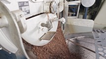 coffee beans falling from a large roasting oven in a coffee factory