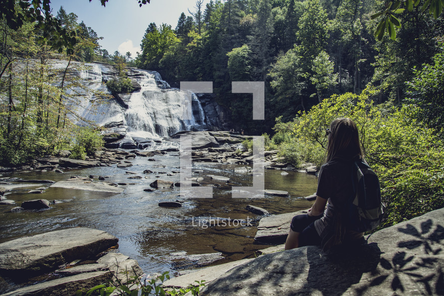 woman sitting watching a waterfall 