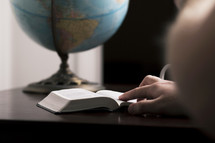 a man reading a Bible and a globe 