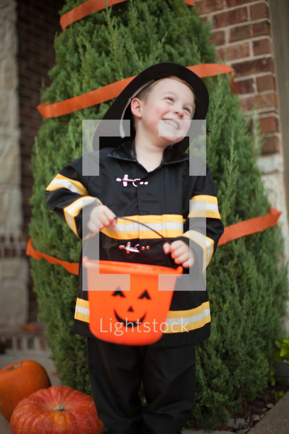 a boy child in a fire fighter costume trick-or-treating on Halloween 