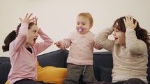 Baby girl playing with 2 young girls, laughing and smiling