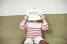child holding a sign that reads Jesus 