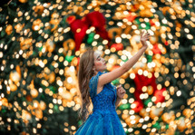 Woman praying and worshiping surrounded with a bokeh of Christmas Lights