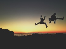 silhouettes of men leaping at sunset