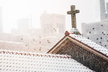 pigeons flying of a church roof covered in snow 