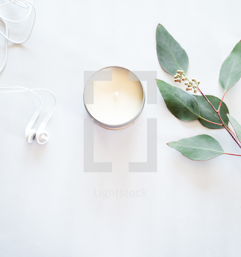 earbuds, candle, twig with leaves
