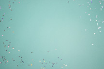 Turquoise background with colorful, shiny star confetti