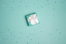 Small present with turquoise background with snowflake confetti
