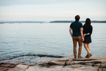 a couple standing on a rocky shore 