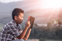 a boy child reading a Bible 
