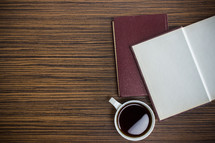 open journal and coffee cup on a desk 
