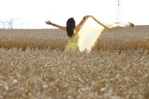 woman dancing in a field of wheat 