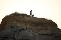 men sitting at the top of a rock peak 