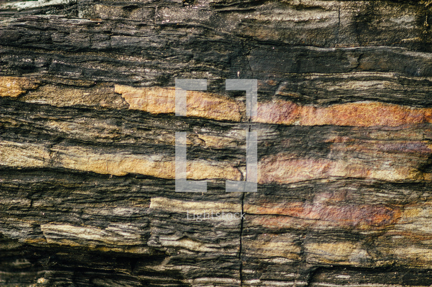 Rock wall with different colored layers.