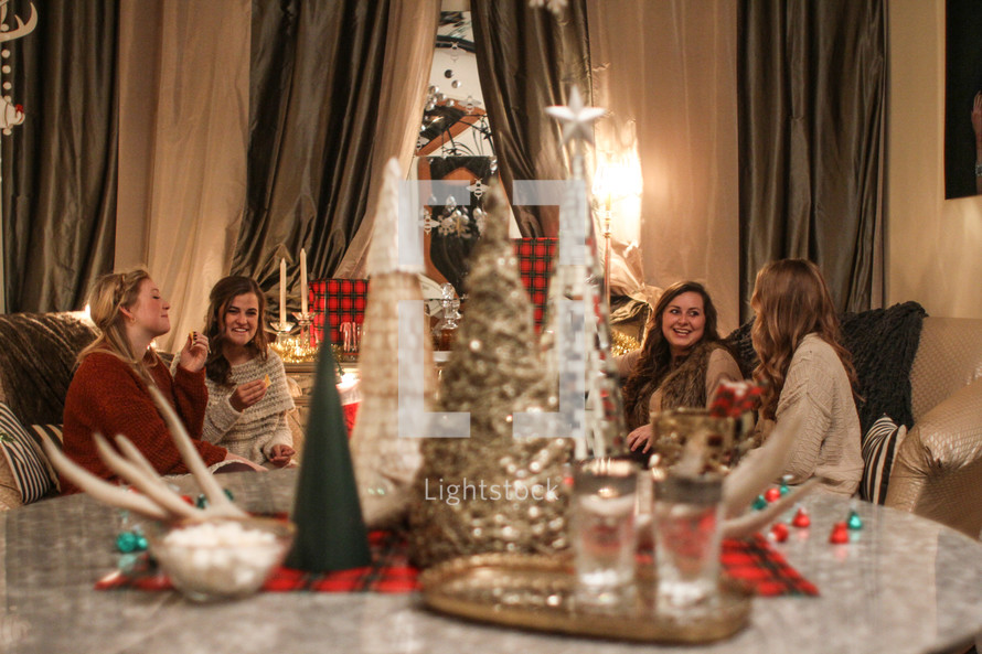 Christmas tree decorations on a table and women gathered in a living room 