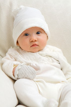 sitting baby dressed in white