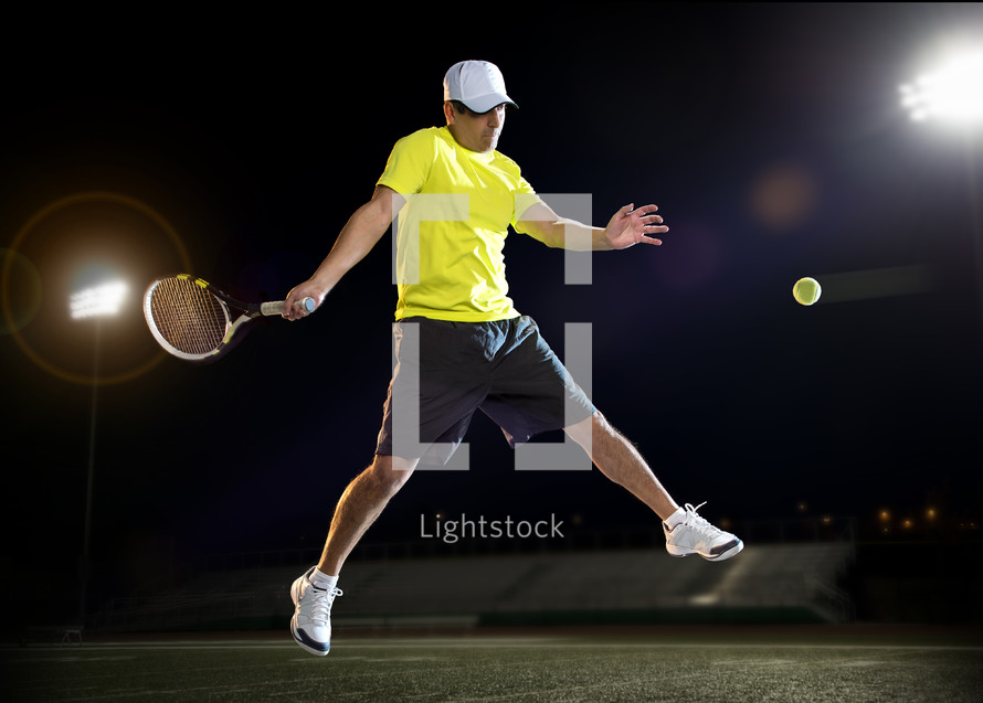 man playing tennis at night