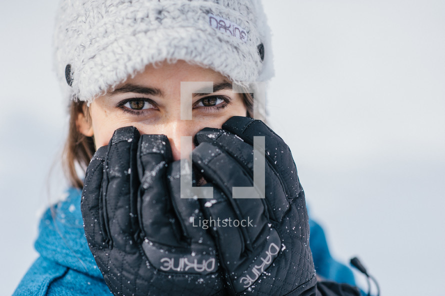 woman with gloves covering her face 