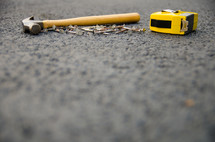 hammer, nails, and tape measure on asphalt 
