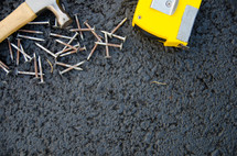 hammer, nails, and tape measure on asphalt