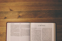 Bible on a wooden table open to the book of 2 Kings.
