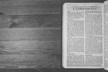 Bible on a wooden table open to the book of 2 Corinthians.