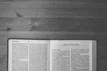 Bible on a wooden table open to the book of Leviticus.