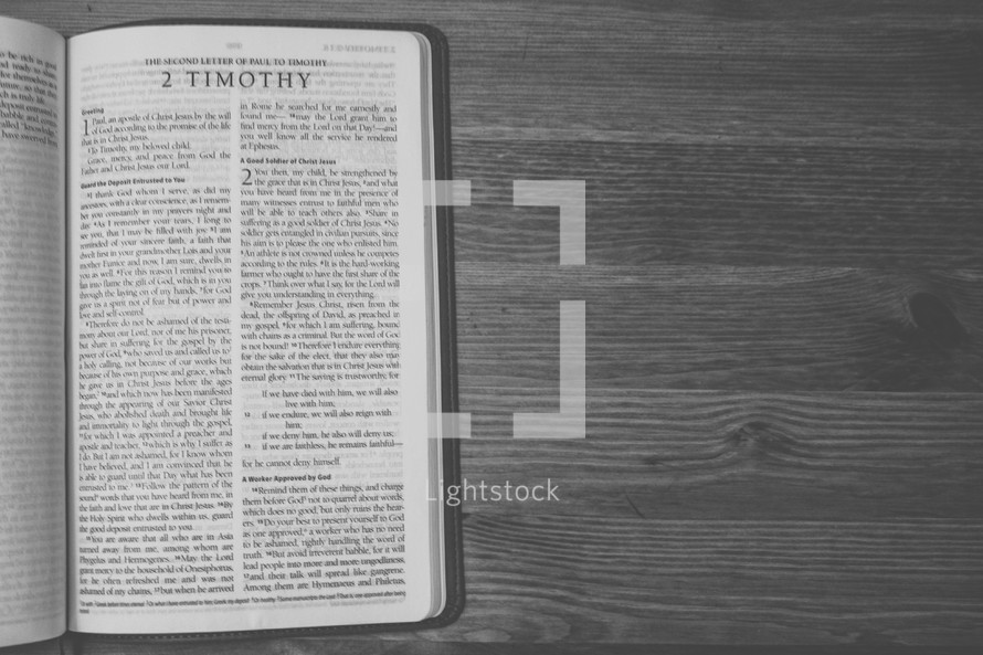 Bible on a wooden table open to the book of 2 Timothy.