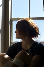 profile of a woman sitting in a a window
