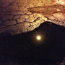 sun reflecting in a puddle on asphalt