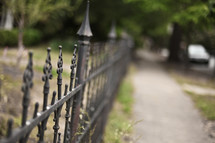 An iron fence lining a sidewalk.