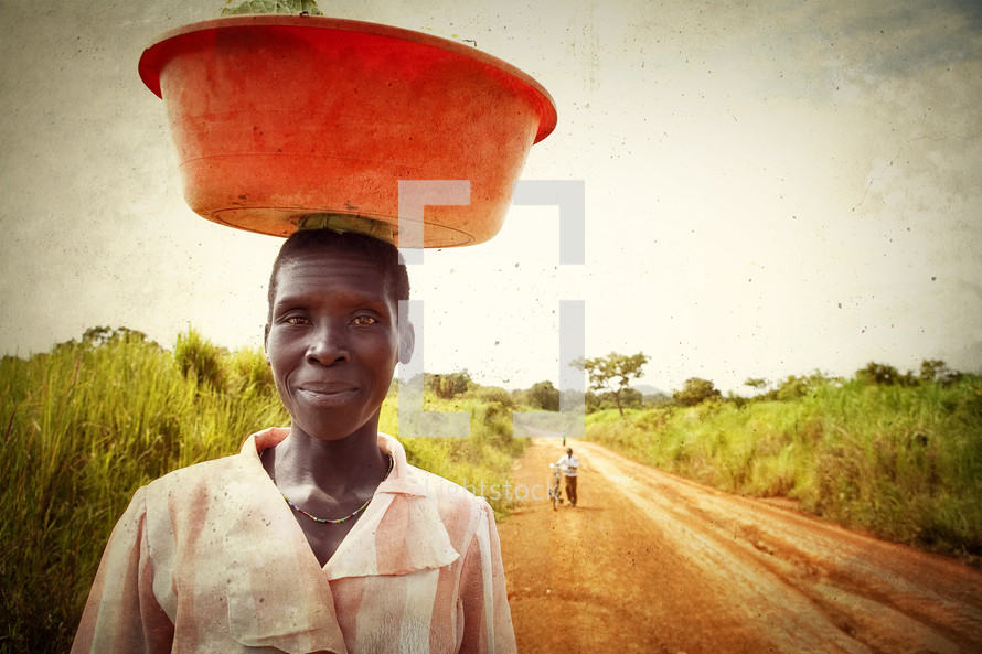African woman carrying bucket on head.