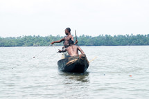 A pair of Nigerians fishing from a dug-out canoe.