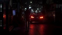 cars and pedestrians in a city at night 