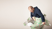 A man breaking free from Christmas wrapping paper