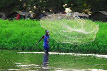 A Sudanese fisherman casting his net/fishing standing on the banks of the Nile River. 