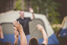 raised hands at a campsite 