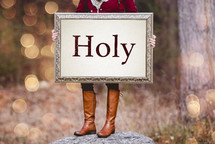 woman holding a canvas sign that reads Holy 
