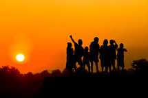 A group of children against a sunset.