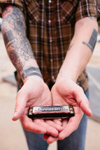 man with tattoos holding a harmonica 