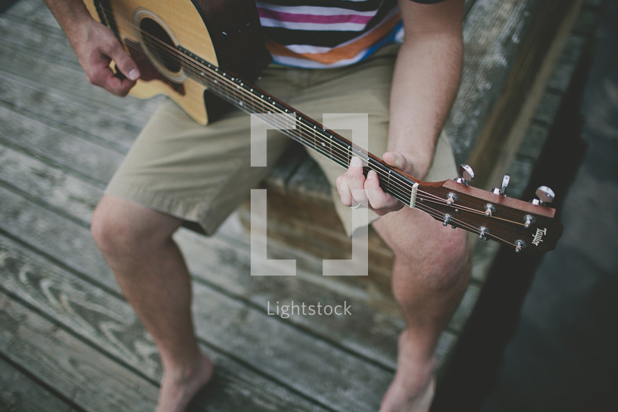 Man playing guitar on the dock
