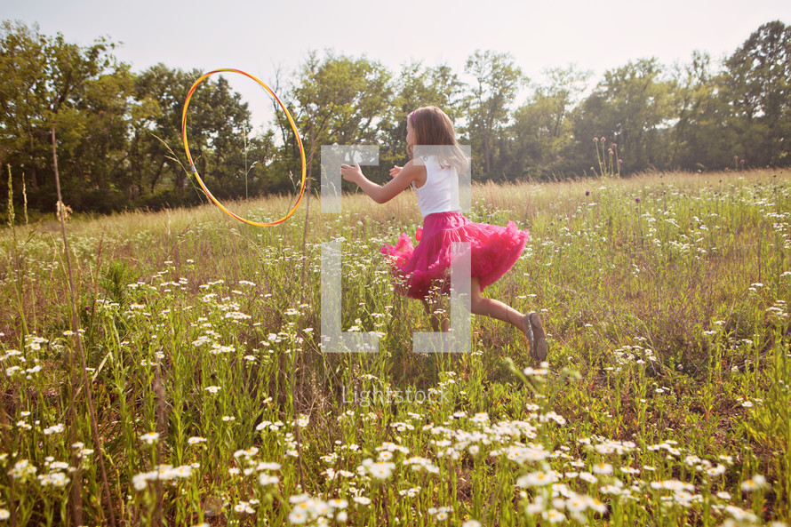 Girl playing with hula hoop in grass field