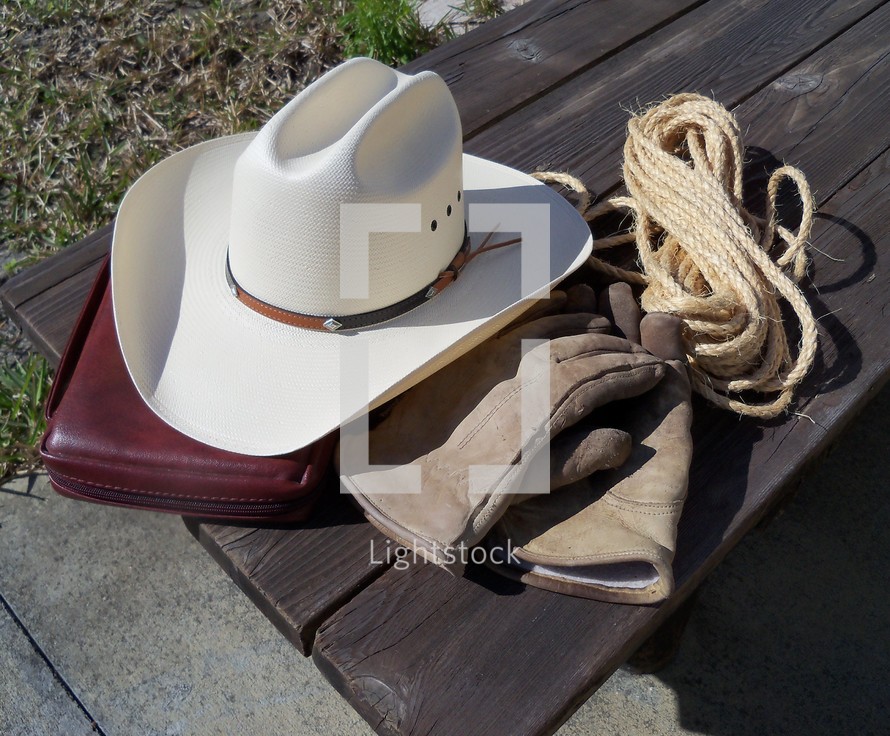 the tools of the trade that a good cowboy cannot do without - A good pair of gloves to do chores, a strong rope for roping cattle, a cowboy hat to shied him from the heat of the sun and the word of God to keep his heart pure.