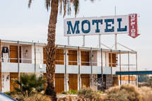 Beachside motel with palm tree in front abandoned old