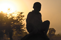 A boy sitting on a rock.