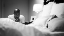 man kneeling in prayer by his bedside 