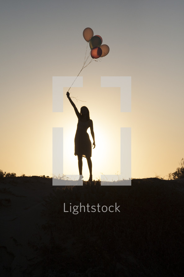 silhouette of a woman holding balloons
